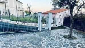 A paved walkway with a stone pattern, a metal gate, and a tree. - S375 - Sirolo, three-room apartment with private courtyard (SIROLO)