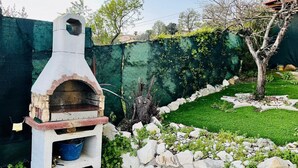 A stone-built outdoor oven with a brick base, surrounded by a stone wall and greenery. - S375 - Sirolo, three-room apartment with private courtyard (SIROLO)
