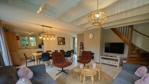 Ein modernes Wohnzimmer mit grauen Sofas, einem runden Couchtisch und einem Fernseher.