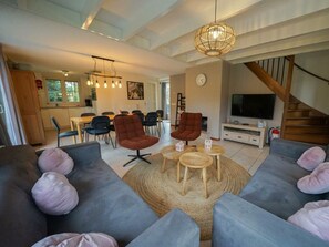 A modern living room with grey sofas, a round coffee table, and a TV. - Villa in Beekbergen With Terrace (Beekbergen)