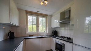 Eine moderne Küche mit weißen Schränken, einer schwarzen Arbeitsplatte, einem Fenster, einem Herd und einer Mikrowelle.