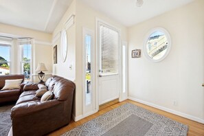 Ein Wohnzimmer mit einem braunen Ledersofa, einer Lampe, einem Teppich und einer Tür, die nach draußen führt.