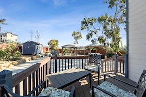 A deck with wooden furniture, a gazebo, and a small shed.