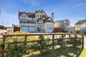 A two-story house with a balcony, a chimney, and a garage.