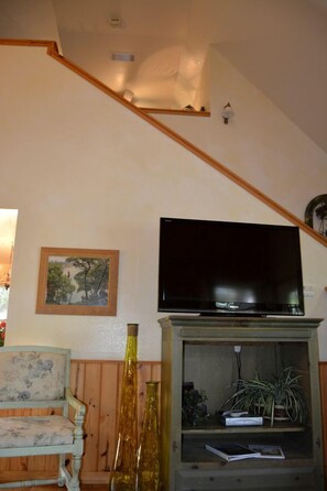 Ein Wohnzimmer mit Fernseher auf einem Holzboden, einem Gemälde an der Wand und einer Holzbank.