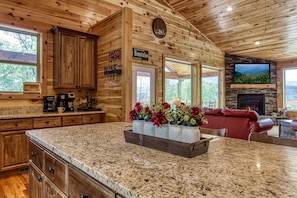A wooden cabin interior with a kitchen, dining area, and living room. - Secluded Rustic Cottage in Gatlinburg, Tennesee - Ideal Spot for a Family Vacation in the Great Smoky Mountains National Park (Gatlinburg)