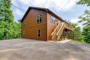 A two-story wooden cabin with a covered porch and a staircase leading to the upper level. - Secluded Rustic Cottage in Gatlinburg, Tennesee - Ideal Spot for a Family Vacation in the Great Smoky Mountains National Park (Gatlinburg)