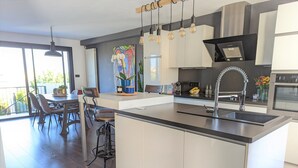 Une cuisine moderne dotée d’un îlot central, d’un éclairage suspendu et d’un coin repas offrant une vue agréable.