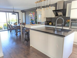 A modern kitchen with a central island, pendant lighting, and a dining area with a view. - Family Vacations: Beautiful, comfortable house with a pool, (Balaruc-les-Bains)