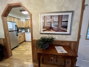A kitchen with wooden cabinets, a refrigerator, and a dining area with a table and a potted plant.