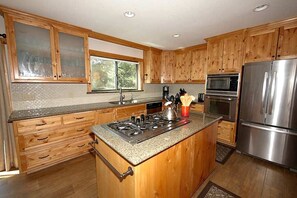 A kitchen with wooden cabinets, a granite countertop, stainless steel appliances, and a window.