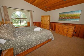Une chambre à coucher avec un lit, une commode en bois et un tableau accroché au mur.