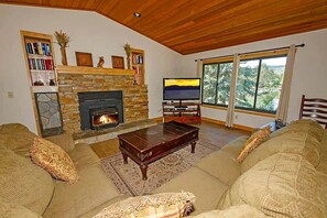 A living room with a stone fireplace, a television, a sofa, and a large window.
