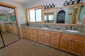 Une salle de bain avec des meubles en bois, deux lavabos et un grand miroir.