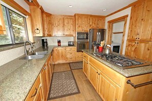 A kitchen with wooden cabinets, granite countertops, a stainless steel sink, a gas stove, and a microwave.