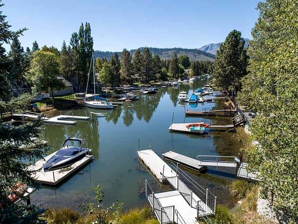 A marina with boats docked, surrounded by trees and hills in the background.