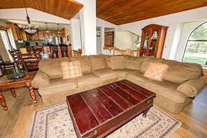 A living room with a sectional sofa, a wooden coffee table, and a rug.
