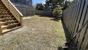 Een achtertuin met een houten trap, een houten hek en een huis op de achtergrond.