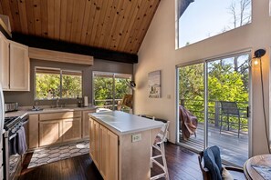 Una cocina moderna con armarios de madera, una isla central y ventanas amplias.