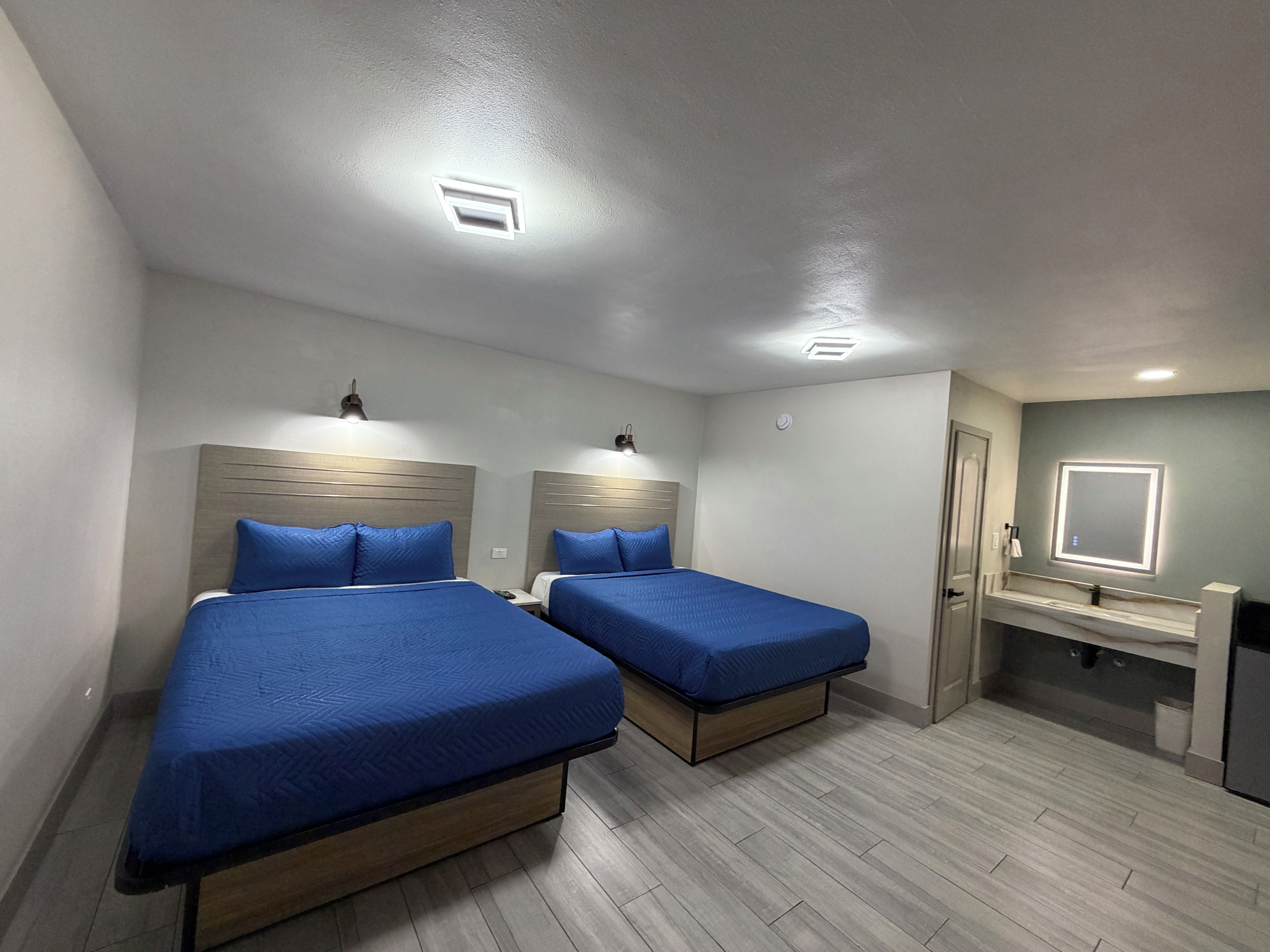 Une chambre d’hôtel avec deux lits, une salle de bain avec un miroir et un petit bureau.