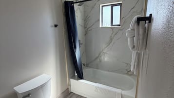 A bathroom with a toilet, a bathtub, and a shower curtain.