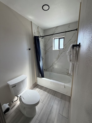 A bathroom with a toilet, a bathtub, and a shower curtain.