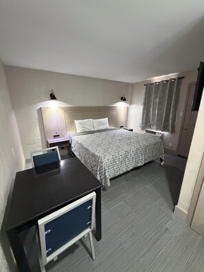 A hotel room with a bed, bedside tables, a desk, and a chair.