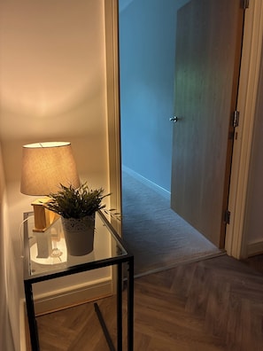 A hallway with a glass table, a lamp, and a potted plant. - Spacious Didsbury Stay | Sleeps 6 | Free Parking (Manchester)
