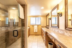 Un bany amb dutxa de vidre, un lavabo amb rentamiques i un mirall.