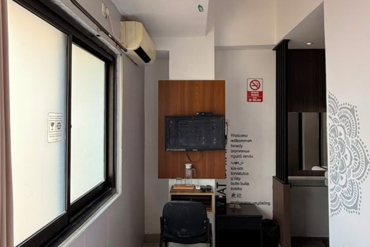 A hotel room with a bed, a desk with a chair, a television, and a window.