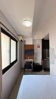 A hotel room with a bed, a desk with a chair, a television, and a window.