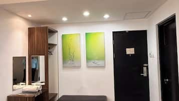 Una habitación con una puerta negra, un banco, dos otomanas, un espejo y obras de arte en la pared.