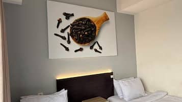 A hotel room with two beds, a headboard, and a wall-mounted artwork.