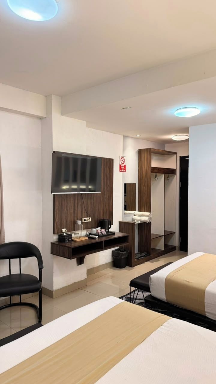 Habitación de hotel con cama, escritorio con televisor de pantalla plana, espejo, armario y zona de estar.