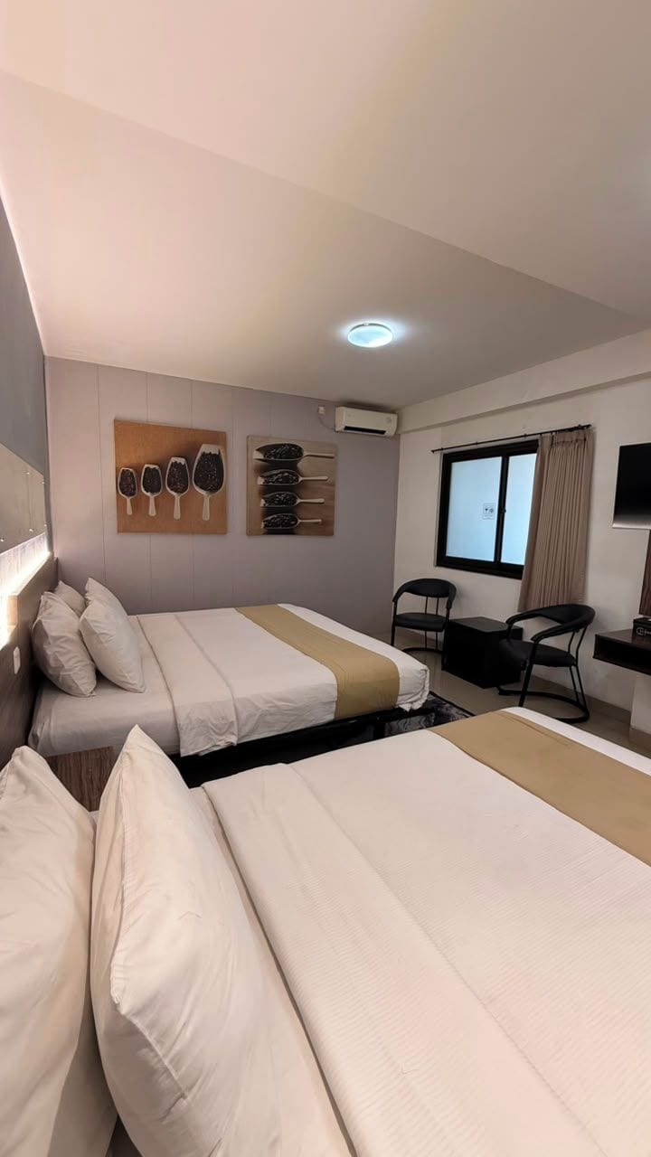 Una habitación de hotel con dos camas, un escritorio, una silla y una ventana.