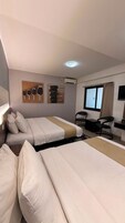 Una habitación de hotel con dos camas, un escritorio, una silla y una ventana.