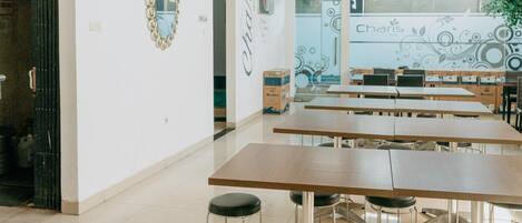 Una habitación amplia con una mesa larga, varias sillas, un ventilador de techo y un gran ventanal con vistas.