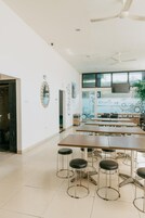 Una habitación amplia con una mesa larga, varias sillas, un ventilador de techo y un gran ventanal con vistas.