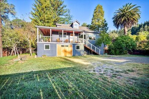 A two-story house with a balcony, a covered porch, and a staircase leading to the upper level. - Stylish Dog-Friendly Cabin with Deck and Yard near Russian River in Monte Rio, California (Monte Río)