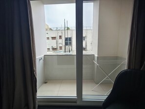 A balcony with a metal railing, a chair, and a view of buildings in the background. - Valuenest (Hyderabad)