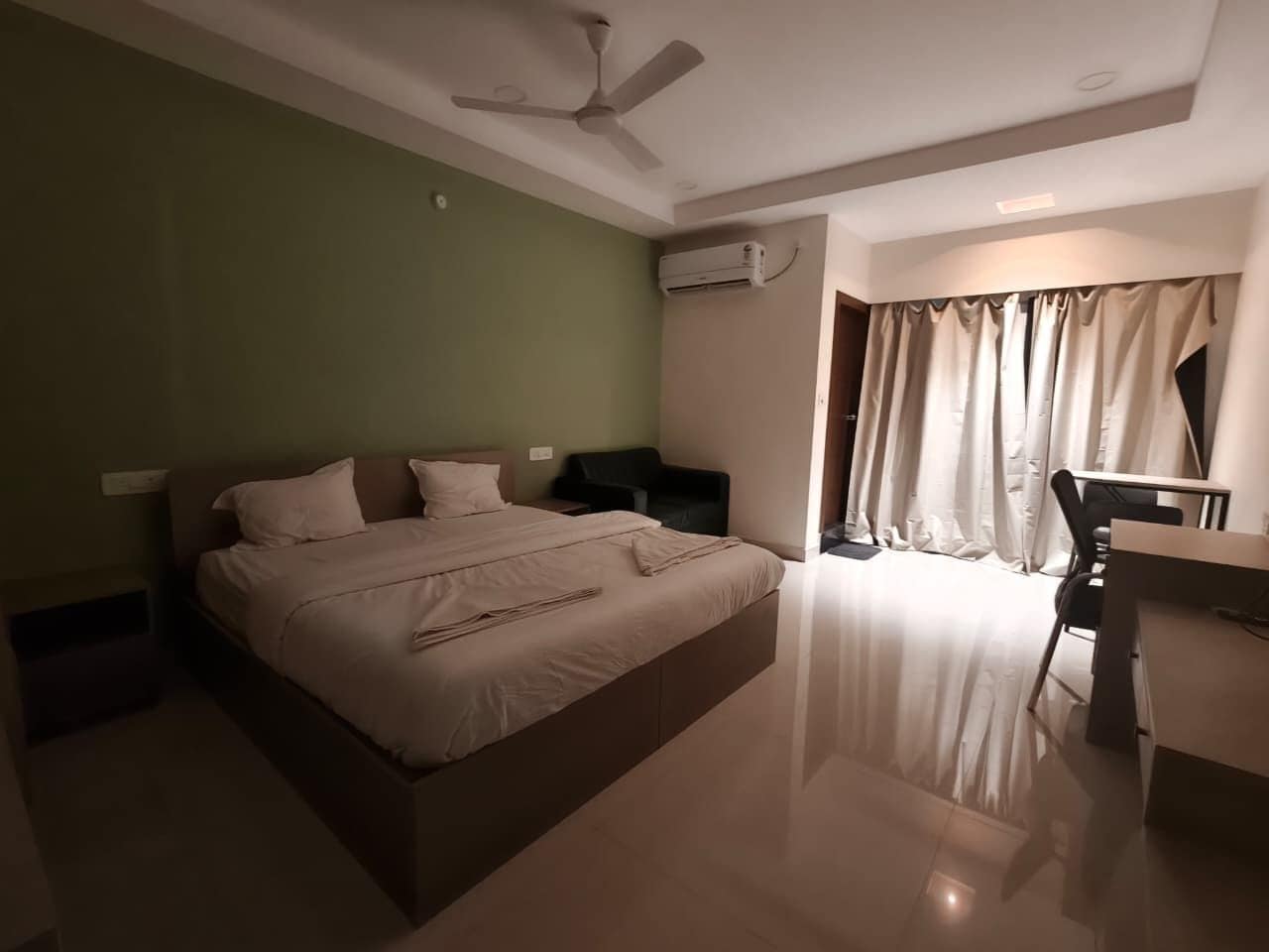 Une chambre d’hôtel équipée d’un lit, d’un bureau, d’une chaise, d’un ventilateur de plafond et d’un appareil de climatisation.