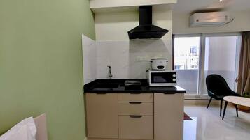 Cocina compacta con microondas, estufa y campana extractora negra.