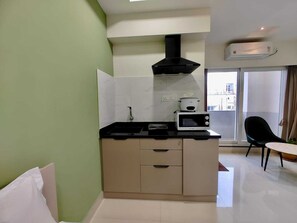 A compact kitchen with a microwave, stove, and black range hood. - Valuenest (Hyderabad)