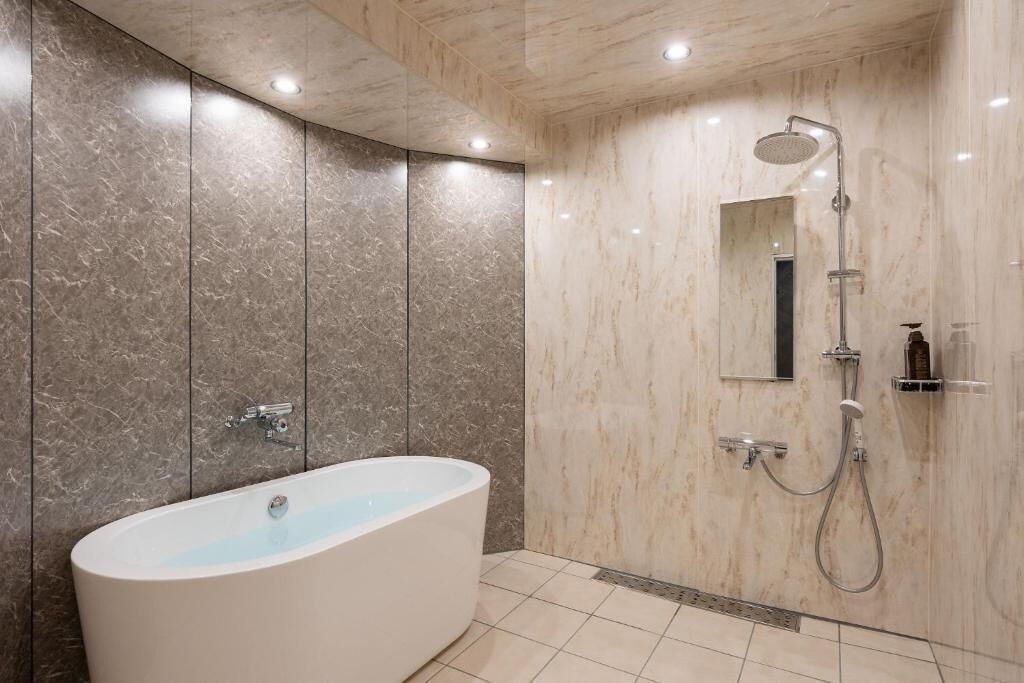 Ein modernes Badezimmer mit einer freistehenden Badewanne, einer Dusche mit Duschbrause und einem wandmontierten Spiegel.