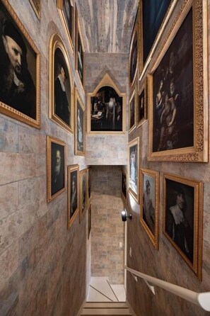 A corridor with framed portraits on the walls, a marble floor, and a staircase leading to an upper level. - JAPAVISTA Enchant (NISHIKUJŌ, KONOHANA WARD)