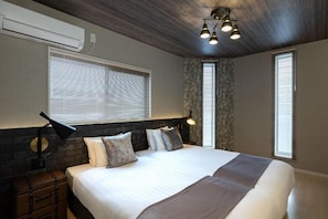 A bedroom with a bed, a suitcase, a lamp, and a ceiling light fixture. - JAPAVISTA Enchant (NISHIKUJŌ, KONOHANA WARD)