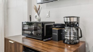 Eine moderne Küche mit Mikrowelle, Kaffeemaschine und Fernbedienung auf einer Holzausziehtafel.