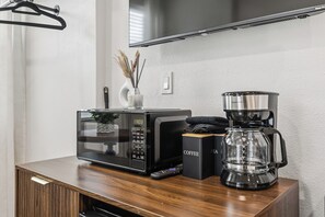 Eine moderne Küche mit Mikrowelle, Kaffeemaschine und Fernbedienung auf einer Holzausziehtafel.