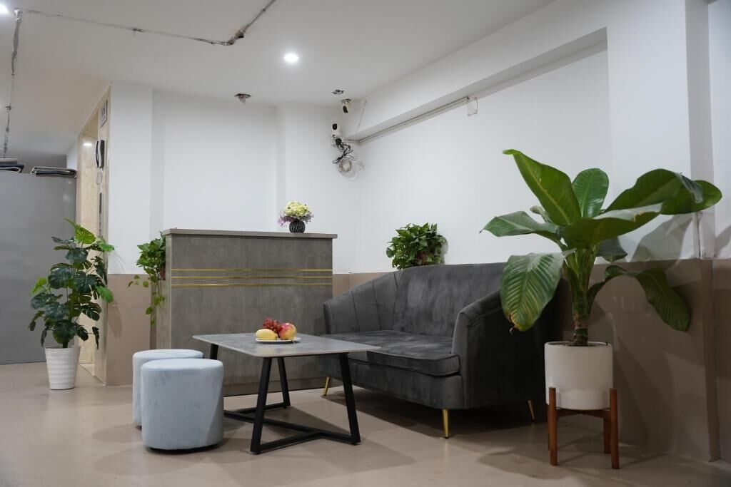 Un salon moderne avec un canapé gris, une petite table ronde sur laquelle sont disposés des fruits et des plantes en pot.