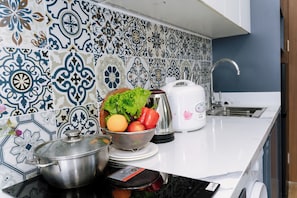 A kitchen with patterned tiles, a sink, a toaster, and a bowl of fruit. - Alaya Lotte Centre Apartment (Ba Dinh)